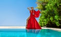 Luxury fashion. Elegant fashion model. Stylish female model in red long gown dress on the Maldives beach. Elegance. Classy woman Royalty Free Stock Photo