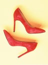 Luxury footwear concept. Footwear with thin high heels, stiletto shoes, top view. Shoes made out of red suede on yellow