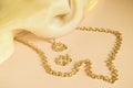 Luxury gold jewelry chain and earrings on pink background with silk, copy space, selective focus Royalty Free Stock Photo