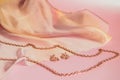 Luxury gold jewelry chain and earrings on pink background with silk, copy space, selective focus Royalty Free Stock Photo