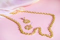 Luxury gold jewelry chain and earrings on pink background with silk, copy space, selective focus Royalty Free Stock Photo