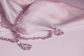 Luxury gold jewelry chain and earrings on pink background with silk, copy space, selective focus Royalty Free Stock Photo