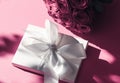 Luxury holiday silk gift box and bouquet of roses on pink background, romantic surprise and flowers as birthday or Valentines Day