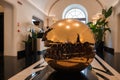 Luxury hotel lobby with cracked gold sphere sculpture, Rome