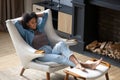 African woman put feet on footstool relaxing on cozy armchair