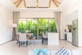 Luxury interior design in living room of pool villas. Airy and bright space with high raised ceiling and kitchen area with dining Royalty Free Stock Photo