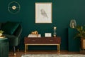 Luxury interior with stylish velvet sofa, wooden commode, pouf, plants, carpet, gold decoration, mock up poster frame.