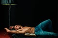 Luxury life. Shirtless muscular bodybuilder man reading book, laying on bed. Royalty Free Stock Photo