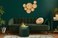 Luxury living room in house with modern interior design, green velvet sofa, coffee table, pouf, gold decoration, plant. Royalty Free Stock Photo