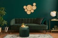 Luxury living room in house with modern interior design, green velvet sofa, coffee table, pouf, gold decoration, plant, lamp. Royalty Free Stock Photo