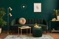 Luxury living room in house with modern interior design, green velvet sofa, coffee table, pouf, gold decoration, plant, lamp. Royalty Free Stock Photo