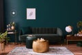 Luxury living room in house with modern interior design, green velvet sofa, coffee table, pouf, gold decoration, plant, lamp. Royalty Free Stock Photo
