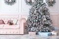 Luxury living room interior with sofa decorated chic Christmas tree, gifts and pillows. Classic interior in pink shades. Christmas