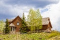 Luxury log cabin with wooden roof and rock bay window on hilltop surrounded by pines and quaking aspens