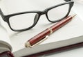 Luxury men`s accessories - stylish black glasses and a pen on an open diary, close-up Royalty Free Stock Photo