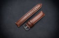 Luxury, minimalist brown tanned leather watch strap on a black surface background