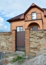 Luxury modern brick house under construction with stone fence and metal entrance door Royalty Free Stock Photo