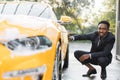 Side view of handsome young busy african man in suit using yellow sponge for cleaning car door Royalty Free Stock Photo