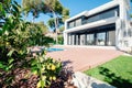 Luxury modern white house with large windows overlooking a Mediterian landscaped garden with palm trees and  blue swimming pool. Royalty Free Stock Photo