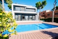 Luxury modern white house with large windows overlooking a Mediterian landscaped garden with palm trees and  blue swimming pool. Royalty Free Stock Photo