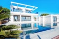 Luxury modern white house with large windows overlooking a Mediterian landscaped garden with palm trees and  blue swimming pool. Royalty Free Stock Photo