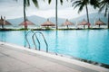 Luxury ocean view tropical resort swimming pool with stainless steel handrail, row of beach umbrella thatched with palm leaves, Royalty Free Stock Photo