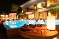 Romantic decor candlelight dinner table setup for party with Champagne special dishes and blurred out light of pool and house Royalty Free Stock Photo