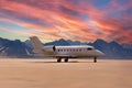 private jet park on ground in desert with mountains in background while sunset ready to start and fly rich VIP business Royalty Free Stock Photo