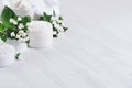 Luxury pure white cosmetics set of natural products for body and skin care - cream, salt, scrub and small flowers on white wood.