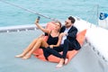 Luxury relaxing couple traveler in nice dress and suite sit on bean bag and drink a glass of wine in part of cruise yacht with Royalty Free Stock Photo