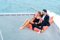 Luxury relaxing couple traveler in nice dress and suite sit on bean bag and drink a glass of wine in part of cruise yacht with Royalty Free Stock Photo