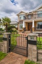 Luxury residential house with palm tree on the front yard behind metal fence. Royalty Free Stock Photo