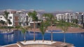 Luxury residential playground with pool, palm trees, modern villas, mountain backdrop, sunny upscale estate for affluent