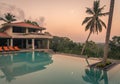 Luxury resort with swimming pool and tropical landscape palm tree at sunset Royalty Free Stock Photo