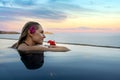 Luxury resort vacation - woman with flower in the hair relaxing in infinity swimming pool with sea view Royalty Free Stock Photo