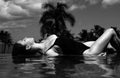 Luxury resort. Woman relaxing in infinity swimming pool. Beautiful model enjoying summer travel vacation, at sea view Royalty Free Stock Photo