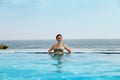 Luxury Resort. Woman Relaxing In Infinity Swimming Pool Water. Beautiful Happy Healthy Female Model Enjoying Summer Travel Vacatio Royalty Free Stock Photo