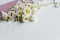 Luxury romantic background: white flowers, pearls necklace, perfume, greeting card on white.accessories and flowers Royalty Free Stock Photo