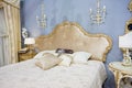 Luxury royal bedroom interior with bed and pillows and classic lighters on blue walls