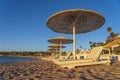 Luxury sand beach with beach chairs and white straw umbrellas in tropical resort in Red Sea coast in Egypt, Africa Royalty Free Stock Photo