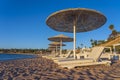 Luxury sand beach with beach chairs and white straw umbrellas in tropical resort in Red Sea coast in Egypt, Africa Royalty Free Stock Photo