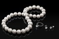 Luxury set white pearl necklace and jewelry with diamonds in ring and earrings on a black background Royalty Free Stock Photo