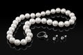 Luxury set white pearl necklace and jewelry with diamonds in ring and earrings on a black background Royalty Free Stock Photo