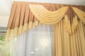 Luxury silk curtain in gold color in the interior of a hotel or apartment, sunlight shines through the window Royalty Free Stock Photo