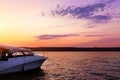 Luxury small fishing motorboat moored near lake or river coast at scenic evening with beautiful dramatic vibrant suset sky on Royalty Free Stock Photo