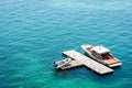 A luxury speedboat moored to an isolated wooden dock in green waters