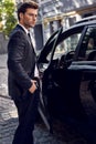 Luxury style. Handsome young businessman entering his car while standing outdoors