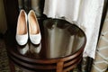 Luxury stylish white wedding shoes on wooden table with a dress in background Royalty Free Stock Photo