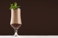 Luxury sweet chocolate cocktail in elegant glass with fresh green mint on dark brown background, copy space.