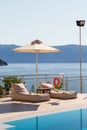 Luxury swimming pool with empty deck chairs or sunbeds and umbrella at resort with beautiful sea view. Royalty Free Stock Photo